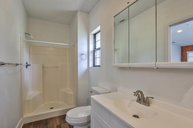 bathroom with hardwood / wood-style floors, walk in shower, vanity, and toilet