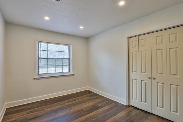 unfurnished bedroom with dark hardwood / wood-style floors and a closet