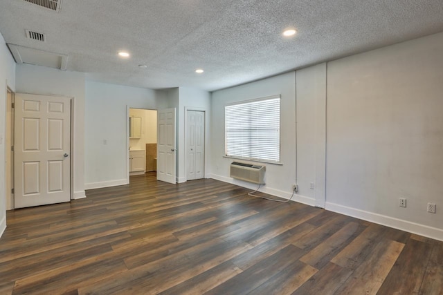 spare room featuring a wall mounted AC, a textured ceiling, and dark hardwood / wood-style floors