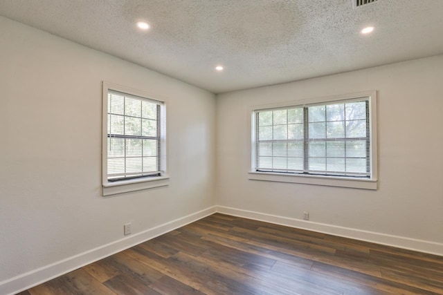 spare room with dark wood-type flooring, a textured ceiling, and plenty of natural light