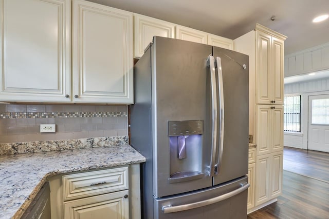 kitchen featuring stainless steel appliances, light stone counters, backsplash, dark wood-type flooring, and cream cabinetry