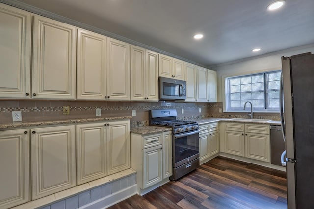 kitchen featuring sink, dark hardwood / wood-style floors, backsplash, light stone countertops, and appliances with stainless steel finishes