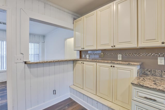 kitchen with crown molding, dark wood-type flooring, light stone counters, and wood walls