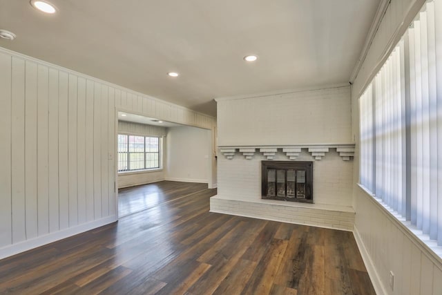 unfurnished living room with a brick fireplace, dark hardwood / wood-style flooring, and ornamental molding