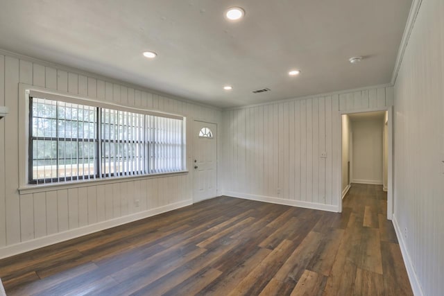 spare room featuring dark hardwood / wood-style floors, wooden walls, and crown molding