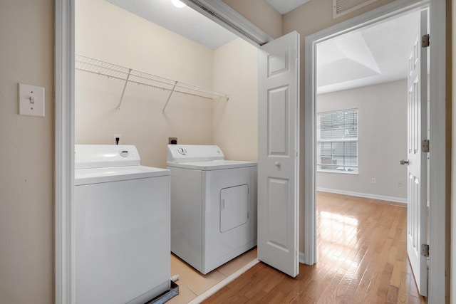 laundry area featuring light hardwood / wood-style flooring and washer and clothes dryer