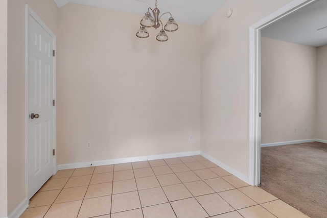 spare room with light colored carpet and an inviting chandelier