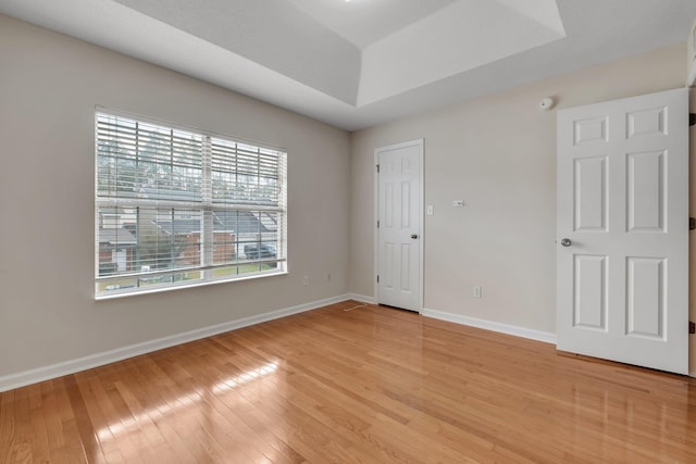 unfurnished room with hardwood / wood-style floors and a tray ceiling