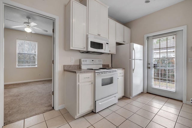 kitchen with white appliances, white cabinets, light colored carpet, and plenty of natural light