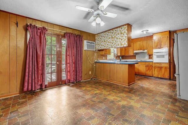 6206 Blountstown Hwy, Tallahassee, FL 32310 - kitchen with oven, under cabinet range hood, freestanding refrigerator, a peninsula, and wooden walls