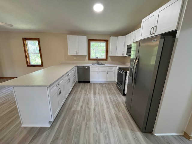 kitchen with white cabinets, kitchen peninsula, appliances with stainless steel finishes, and plenty of natural light