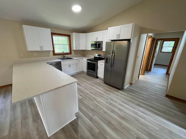 kitchen featuring stainless steel appliances, white cabinets, sink, and vaulted ceiling