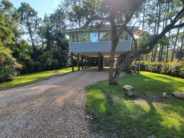 view of front of home with a front lawn, a sunroom, and a carport