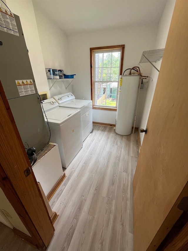 laundry area with washer and clothes dryer, electric water heater, and light hardwood / wood-style floors