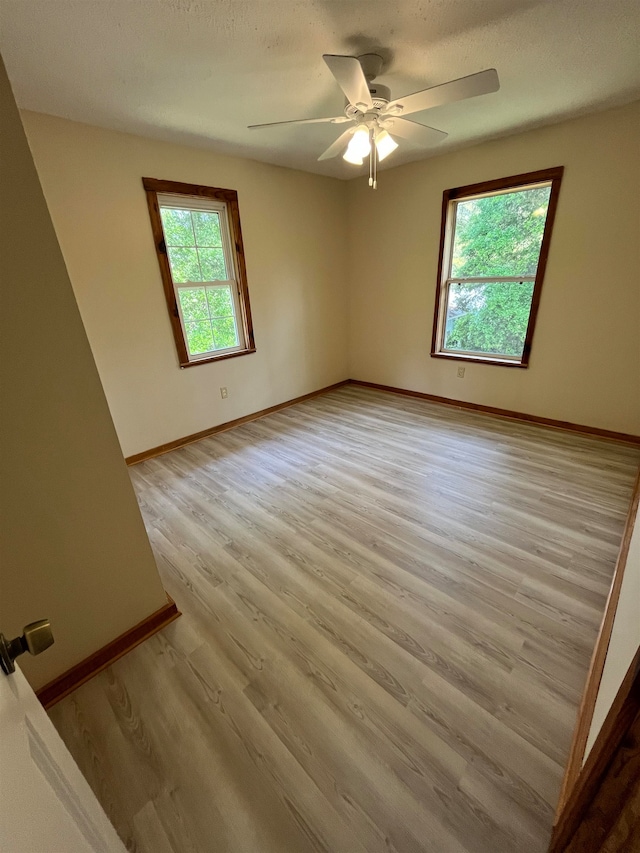 unfurnished room with a textured ceiling, light wood-type flooring, and ceiling fan