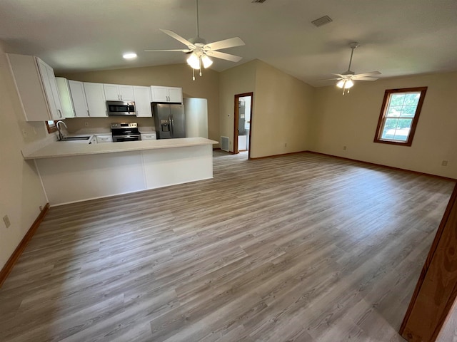 kitchen featuring stainless steel appliances, light hardwood / wood-style floors, white cabinets, kitchen peninsula, and lofted ceiling