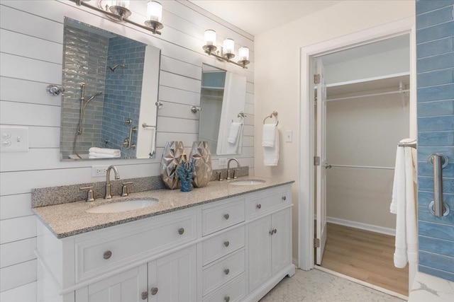 bathroom featuring vanity, wooden walls, and walk in shower