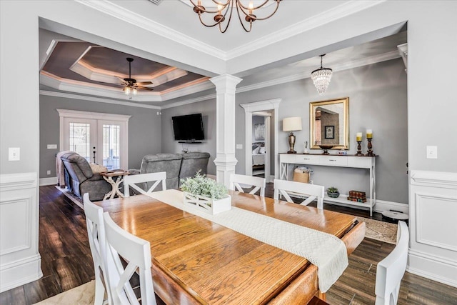 dining area with ceiling fan with notable chandelier, wood finished floors, ornate columns, a tray ceiling, and crown molding
