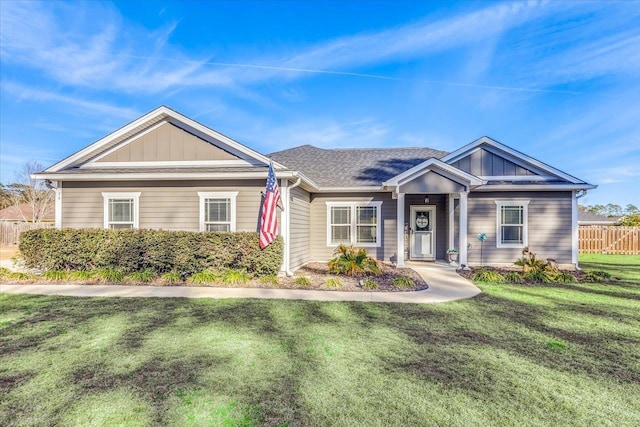 view of front of home featuring board and batten siding, a front yard, fence, and a shingled roof