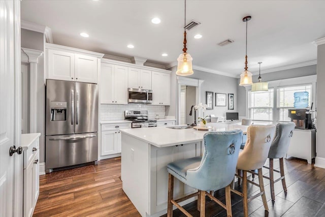 kitchen featuring visible vents, stainless steel appliances, a sink, and ornamental molding