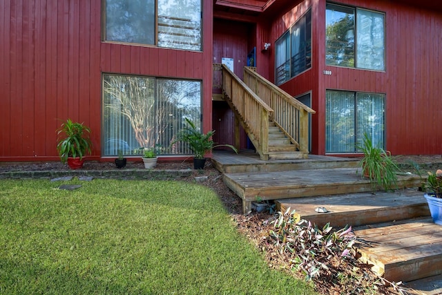 entrance to property featuring a lawn and a deck