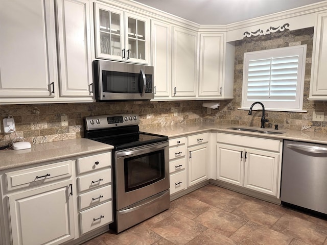 kitchen featuring light countertops, decorative backsplash, appliances with stainless steel finishes, white cabinets, and a sink