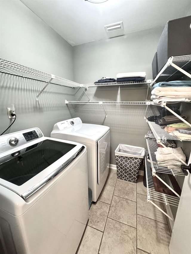 clothes washing area featuring laundry area, light tile patterned floors, and separate washer and dryer