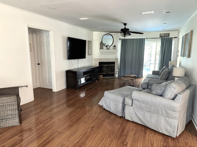 living room featuring ceiling fan, a tiled fireplace, wood finished floors, and baseboards