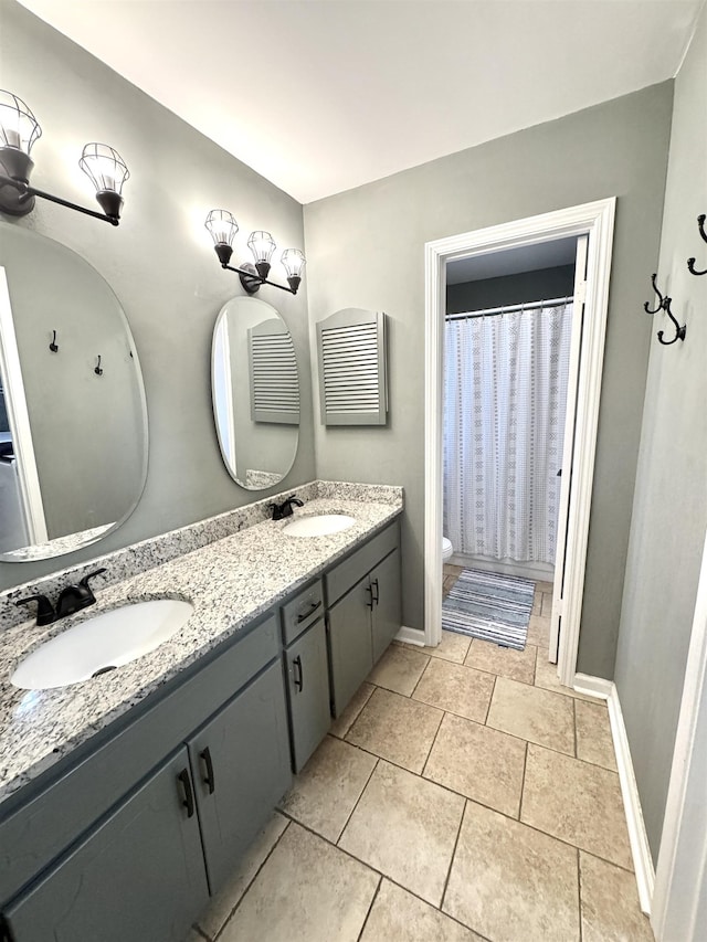 full bath featuring baseboards, a sink, toilet, and double vanity