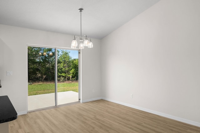 spare room featuring wood-type flooring and a chandelier