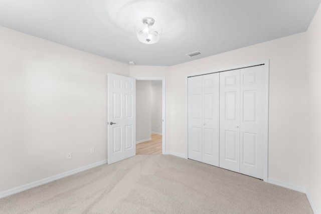 unfurnished bedroom with light colored carpet and a closet