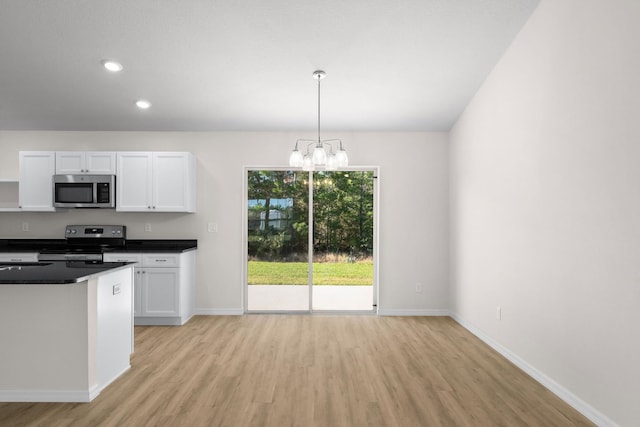 kitchen with hanging light fixtures, white cabinets, stainless steel appliances, and light hardwood / wood-style floors