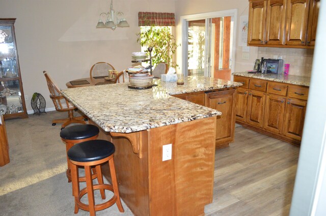 kitchen featuring light hardwood / wood-style floors, light stone counters, hanging light fixtures, a chandelier, and a kitchen island