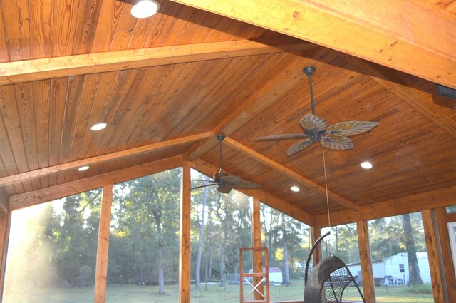 unfurnished sunroom with lofted ceiling with beams, wooden ceiling, ceiling fan, and plenty of natural light