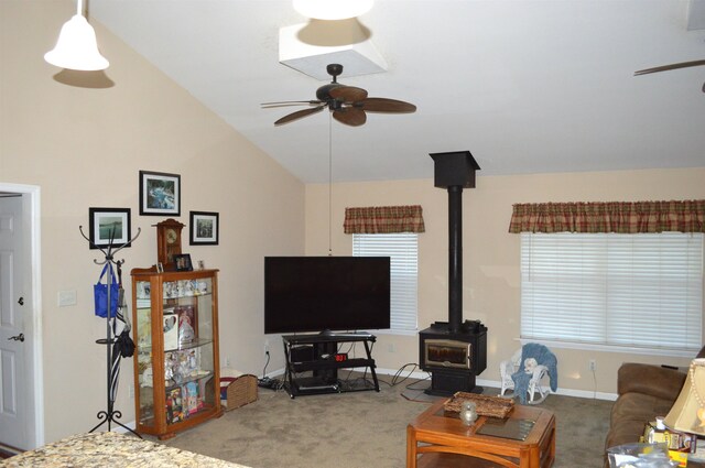 carpeted living room featuring a wood stove, lofted ceiling, and ceiling fan