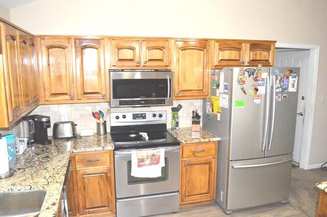 kitchen featuring decorative backsplash, stainless steel appliances, and light stone countertops