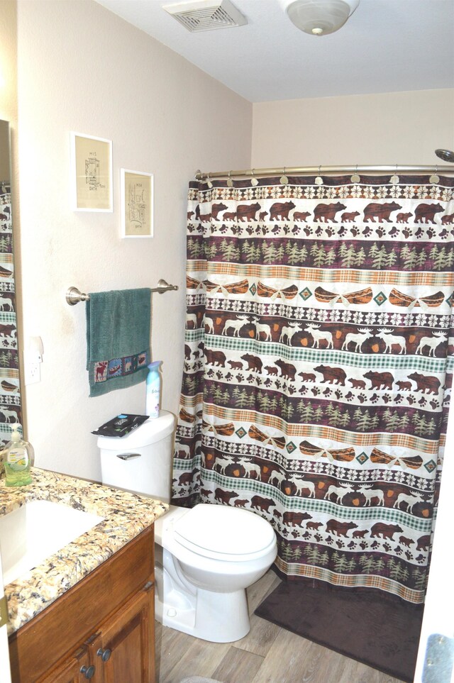 bathroom with curtained shower, vanity, hardwood / wood-style flooring, and toilet