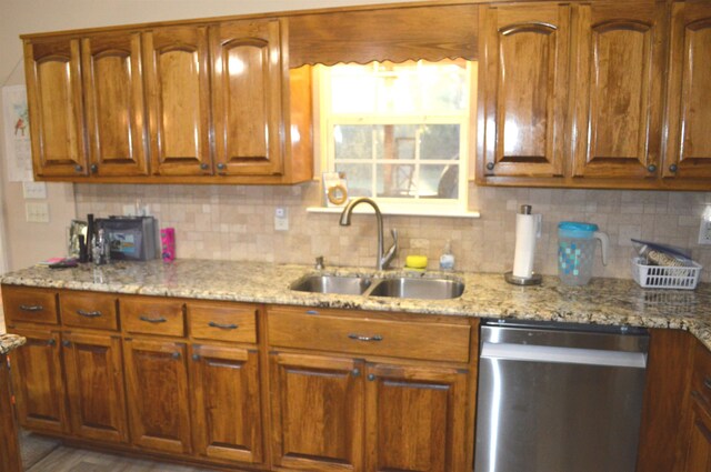 kitchen featuring stainless steel dishwasher, light stone countertops, sink, and decorative backsplash