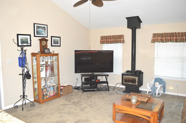 living room featuring ceiling fan, carpet flooring, a wood stove, and lofted ceiling