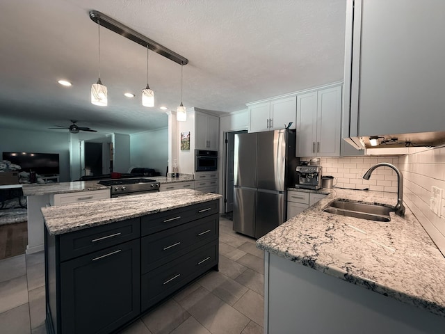 kitchen featuring decorative backsplash, light stone countertops, stainless steel appliances, and a sink