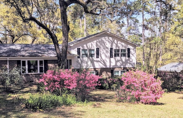 tri-level home with brick siding and a front lawn