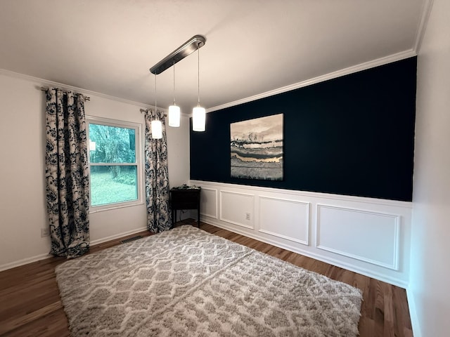 unfurnished dining area with wainscoting, wood finished floors, and ornamental molding