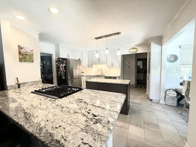 kitchen featuring crown molding, a peninsula, freestanding refrigerator, gas stovetop, and a sink