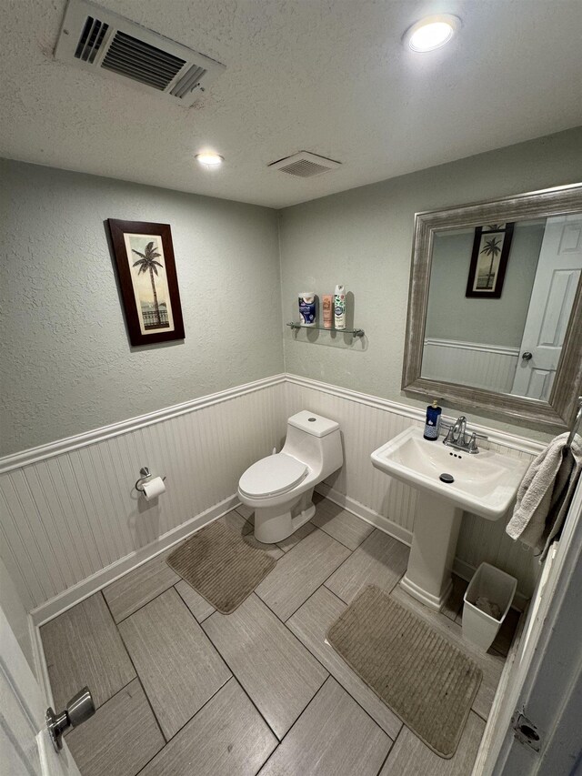 2408 Ionic Ct, Tallahassee, FL 32303 - bathroom with wainscoting, a textured ceiling, and recessed lighting