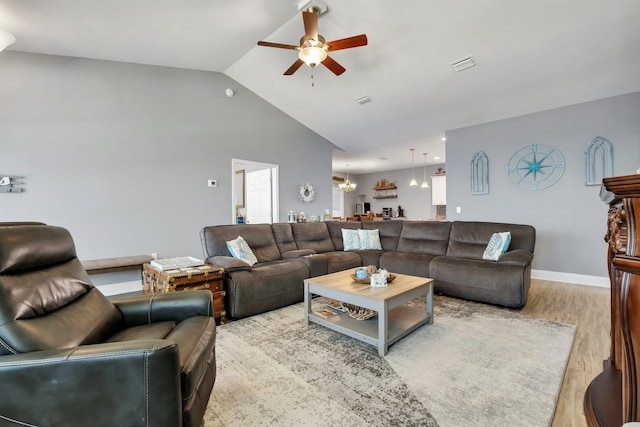 living room featuring ceiling fan with notable chandelier, light wood-type flooring, and lofted ceiling