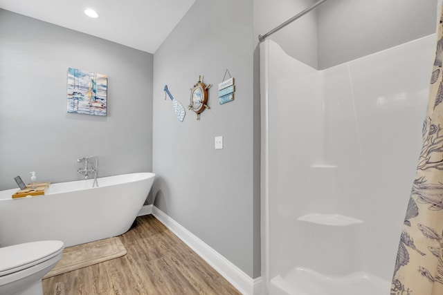 bathroom featuring hardwood / wood-style flooring, toilet, and a tub to relax in