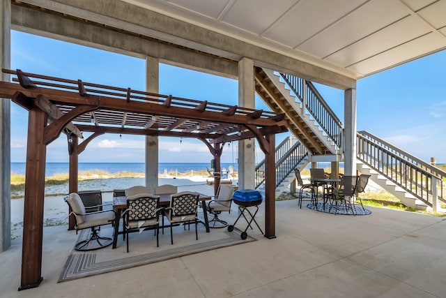 view of patio / terrace with a pergola, a water view, and a view of the beach