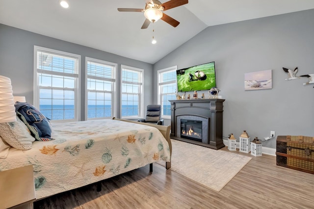 bedroom with multiple windows, hardwood / wood-style flooring, vaulted ceiling, and ceiling fan