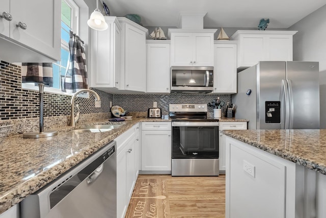 kitchen featuring tasteful backsplash, stainless steel appliances, sink, decorative light fixtures, and white cabinetry