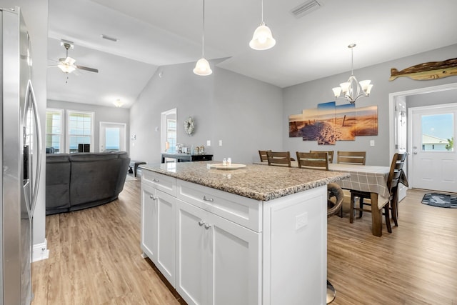 kitchen featuring white cabinetry, hanging light fixtures, stainless steel fridge, a kitchen island, and light wood-type flooring